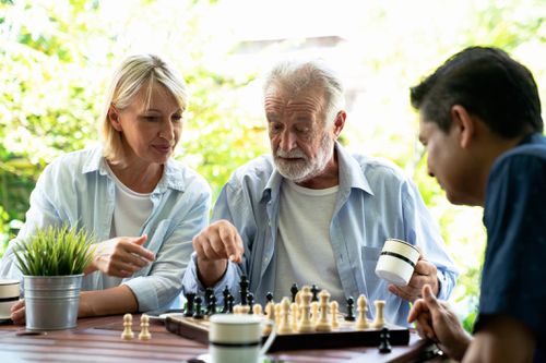 man with alzheimer's disease playing chess with loved ones