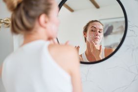Mirror reflection of young female doing an anti-aging skincare routine