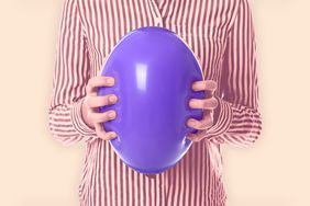 Woman squeezing purple balloon, closeup