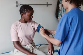 Nurse checking blood pressure of female patient in clinic