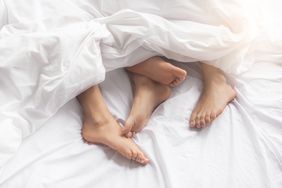 The feet of a couple underneath the covers