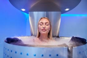 Portrait of happy young woman in a whole body cryotherapy cabin with her eyes closed. 