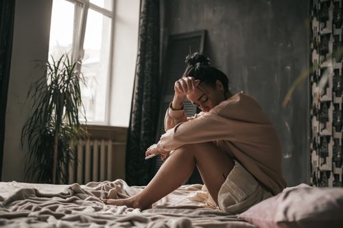 young woman sitting on her bed feeling sad 