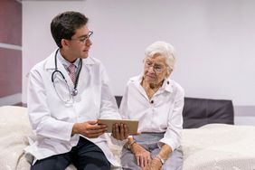 Young doctor explaining to elderly patient using a tablet.