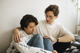 man sitting with friend and consoling him