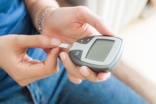 A young woman is using a glucometer to test her blood sugar level