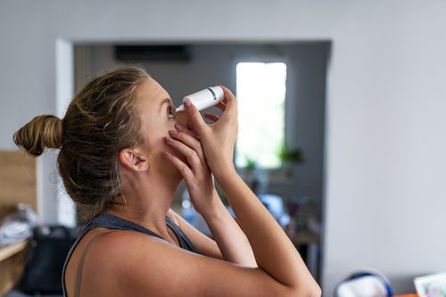 Young woman putting in eyedrops