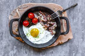 Fried egg with bacon and tomatoes on a cast iron pan