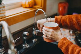 Woman filling up cup with water from the faucet