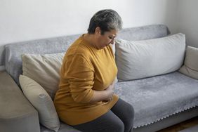 Woman sitting on couch holding her stomach