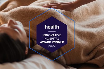 Health Innovative Hospital Award Winner 2022 Badge with a woman lying in the background with a gentle hand on top. 