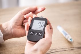 Close-up of woman hands measuring glucose level blood test with glucometer.