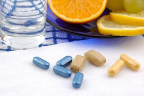 vitamin supplements in front of a glass of water and citrus