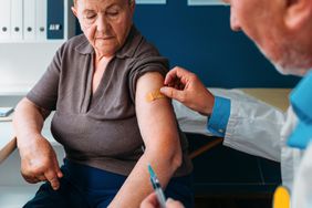 senior woman receiving bandage after covid vaccine booster