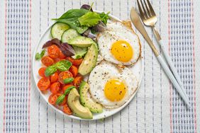 A high protein breakfast plate of eggs, avocado, and cherry tomatoes