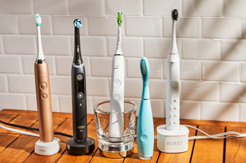 An assortment of electric toothbrushes displayed on wood table