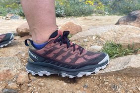 A woman stands on a rock while wearing Merrell Speed Eco Hiking Shoes