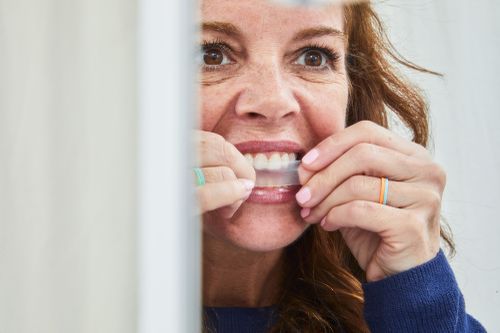 Women using whitening strips on her teeth