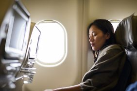 An Asian woman sleeping on an airplane