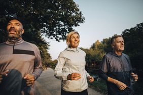 Smiling female with friends looking away while jogging in park during sunset