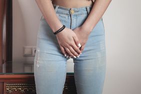 A young woman with her hands on her pelvic area