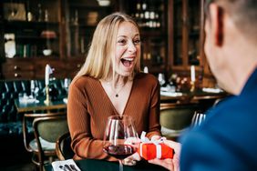 A woman excited to receive a gift at a restaurant