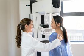 lab technician helping woman get a mammogram