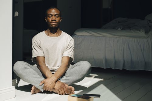man practicing mindfulness in bedroom with sunlight