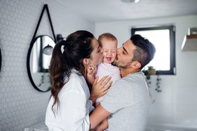 Parents kissing their toddler child in the bathroom