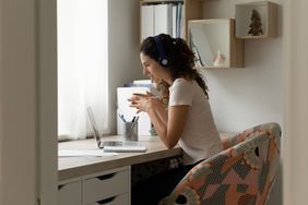 Woman sit at desk using laptop participates in online therapy call 