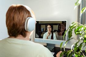 Senior adult woman having online psychotherapy session with professional psychologist using computer at home
