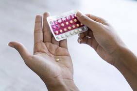 Woman holding birth control pills at home