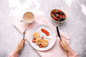woman eating her breakfast with cottage cheese pancakes and strawberry at home
