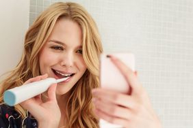 Woman brushing teeth, taking selfie