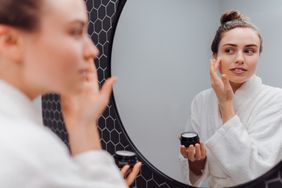A young woman in a bathrobe applying her skincare routine