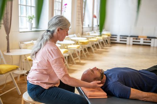 Woman practicing Somatic therapy on a man, in her health studio