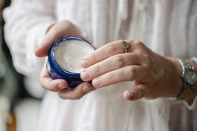 A person opening a jar of hand cream