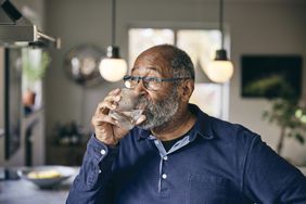 A black senior man drinking a cup of water while he's water fasting