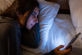 Woman awake at night in bed looking at smartphone